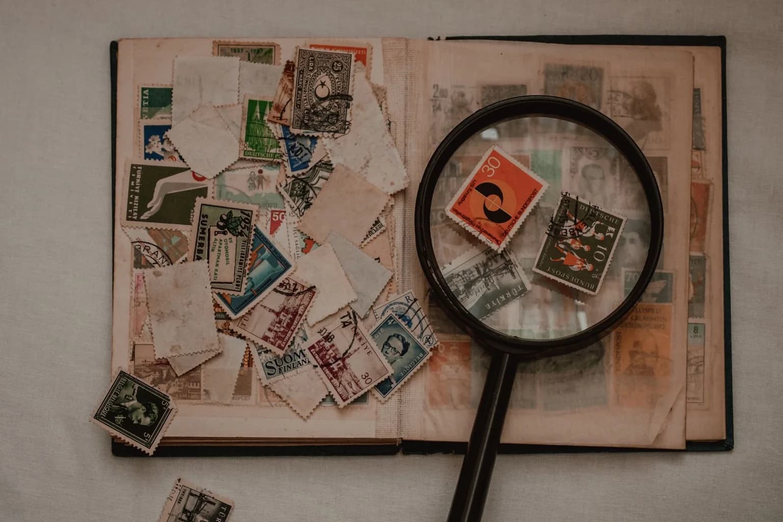 Album de timbres anciens et pièces isolées examinés à la loupe
