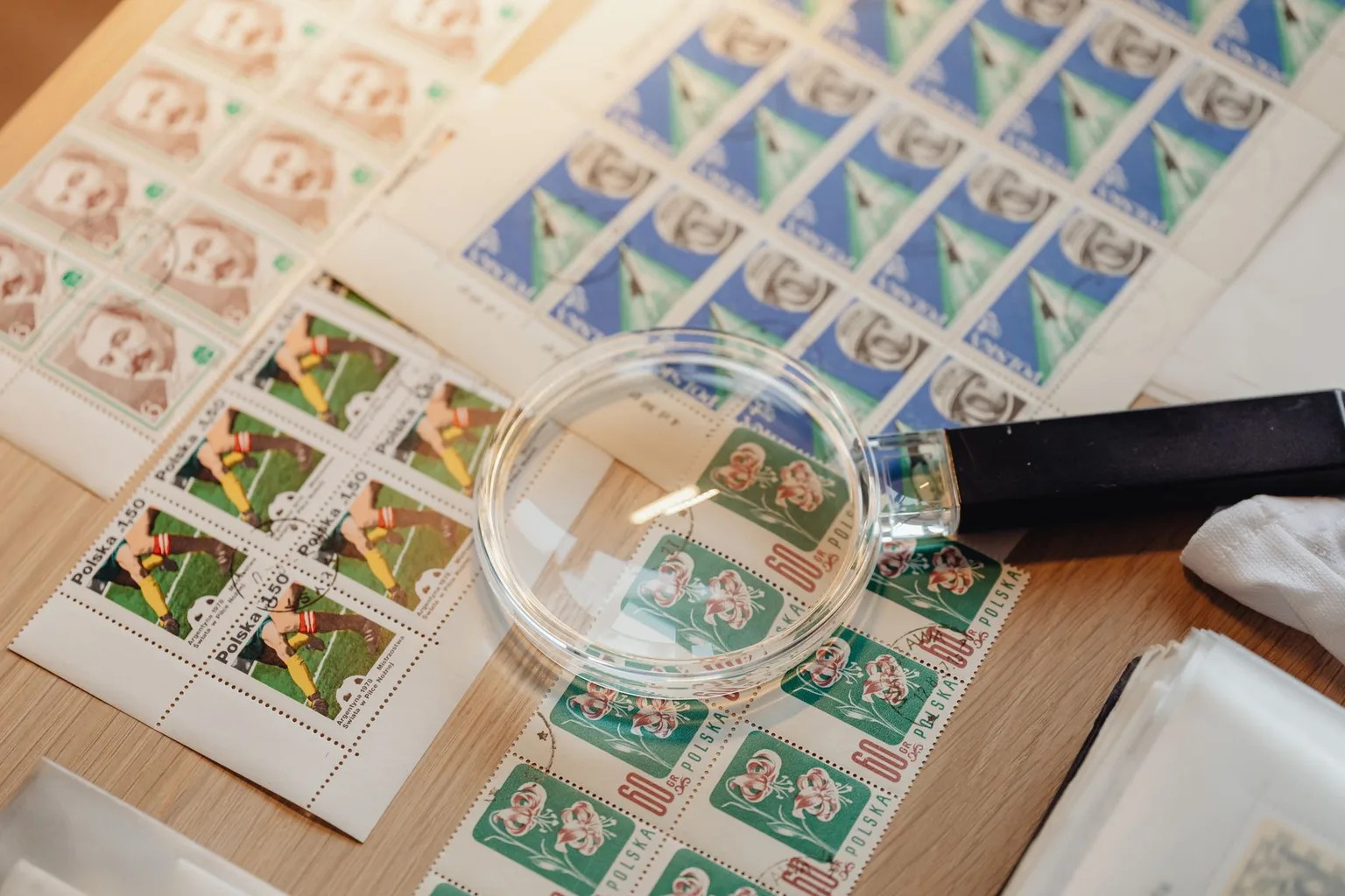 Sheets of postage stamps examined with a magnifying glass on a collector table